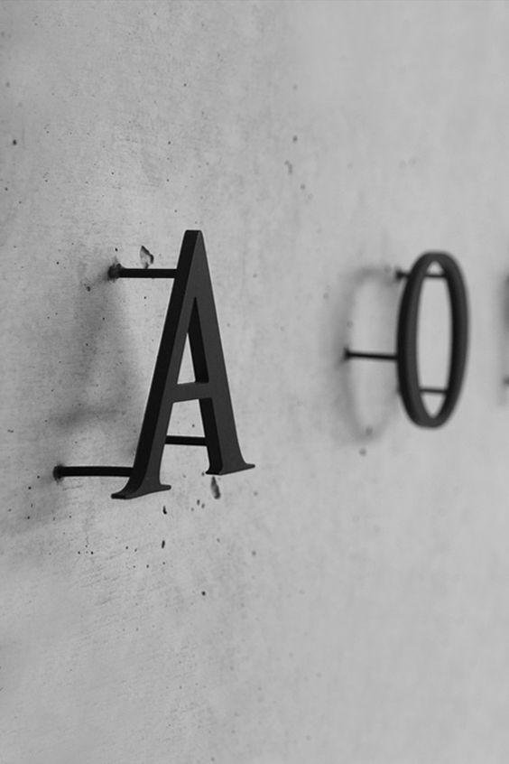 Black signage on pins against a concrete background...