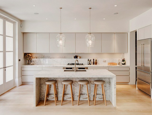 Clean cut off white kitchen with marble island and counters